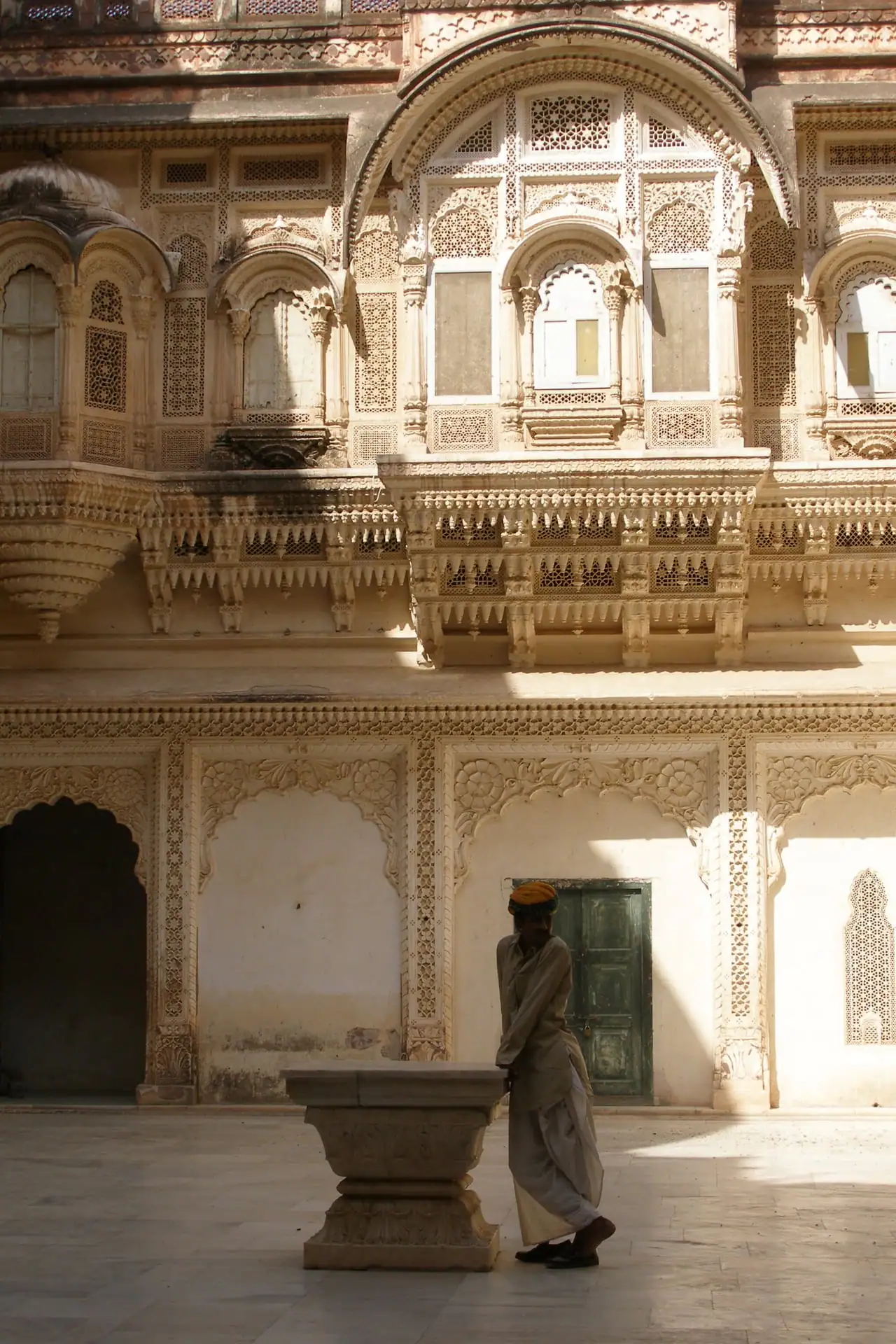 A palace courtyard framed by carved sandstone jharokhas