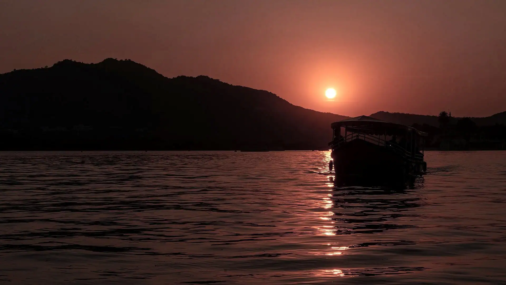 The sun setting over the hills of Lake Pichola, a path of light on the water